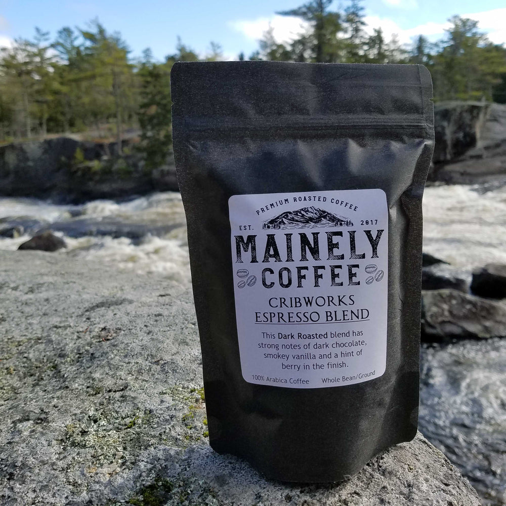 Mainely Coffee bag on a rock with a scenic background.