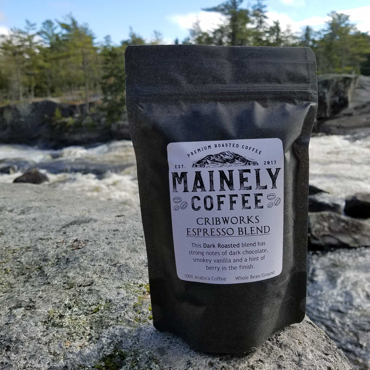 Mainely Coffee bag on a rock with a scenic background.