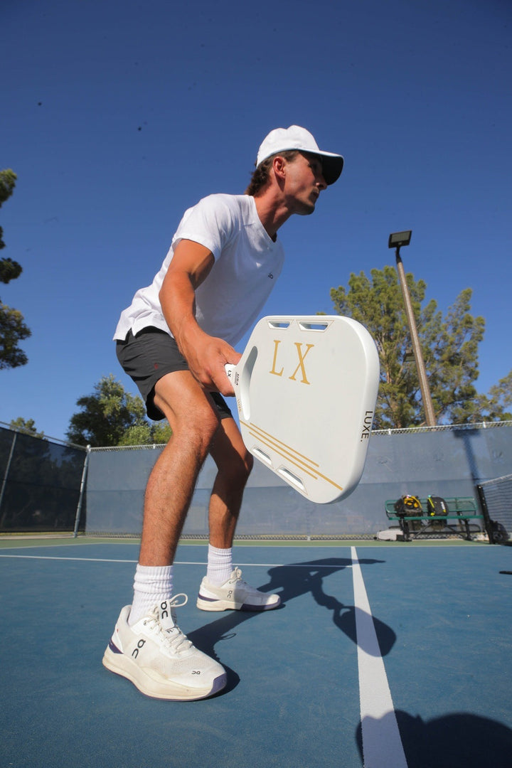 Person playing pickleball on a court with a clear blue sky.