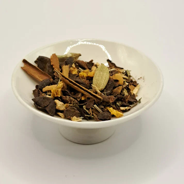White bowl filled with dried tea herbs on a white background