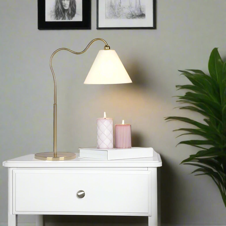 Ornate Brass Ring Base Curved Table Lamp with Triangle White Drum Shade in Room.