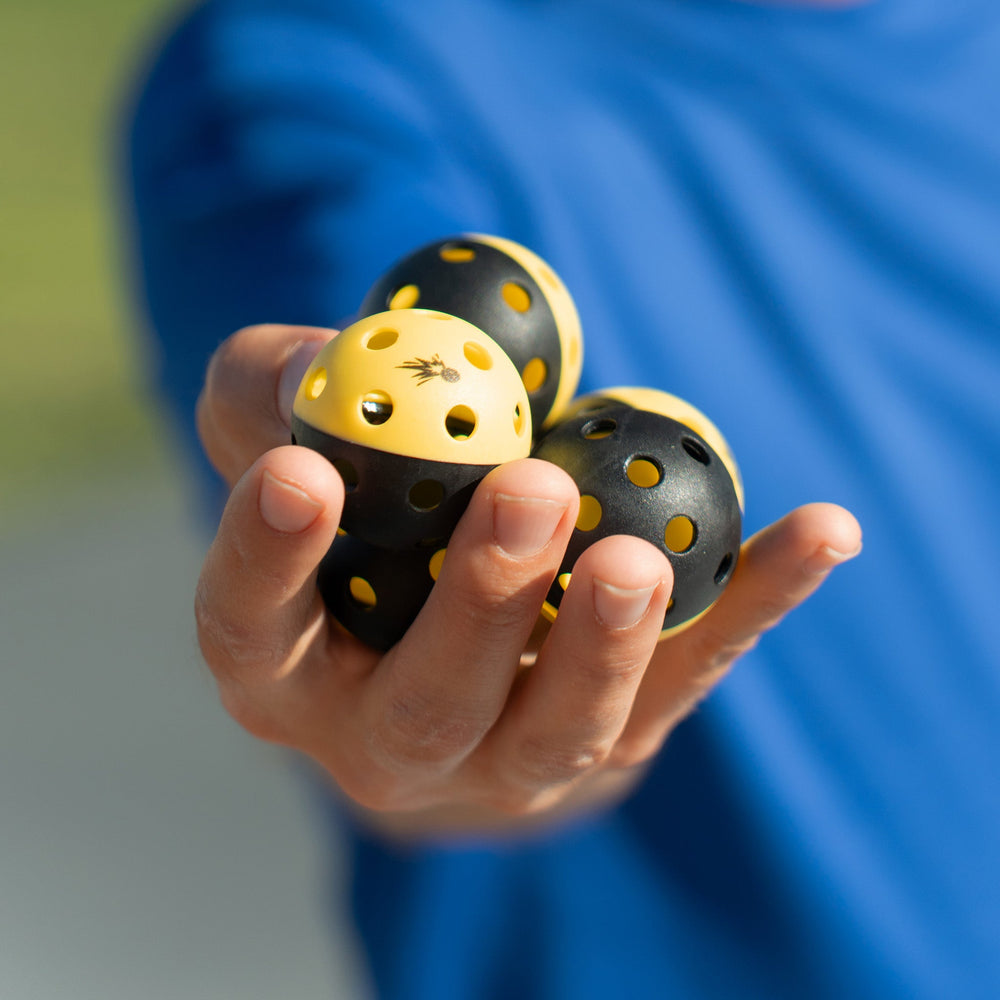 Moment Pickleblasters 2-Color Mini Plastic Indoor/Outdoor Practice Balls for Pickleball Training in Hand.