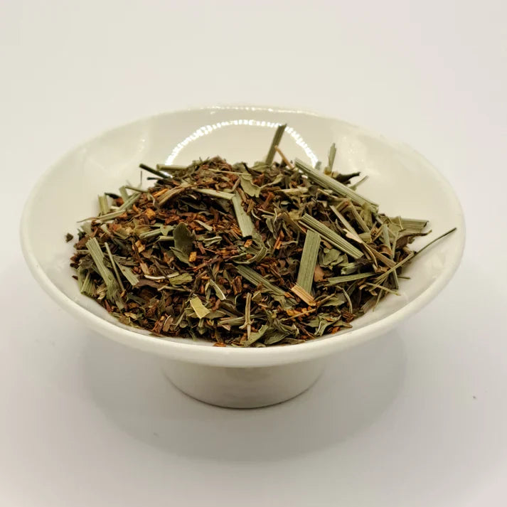 White bowl filled with dried tea herbs on a white background