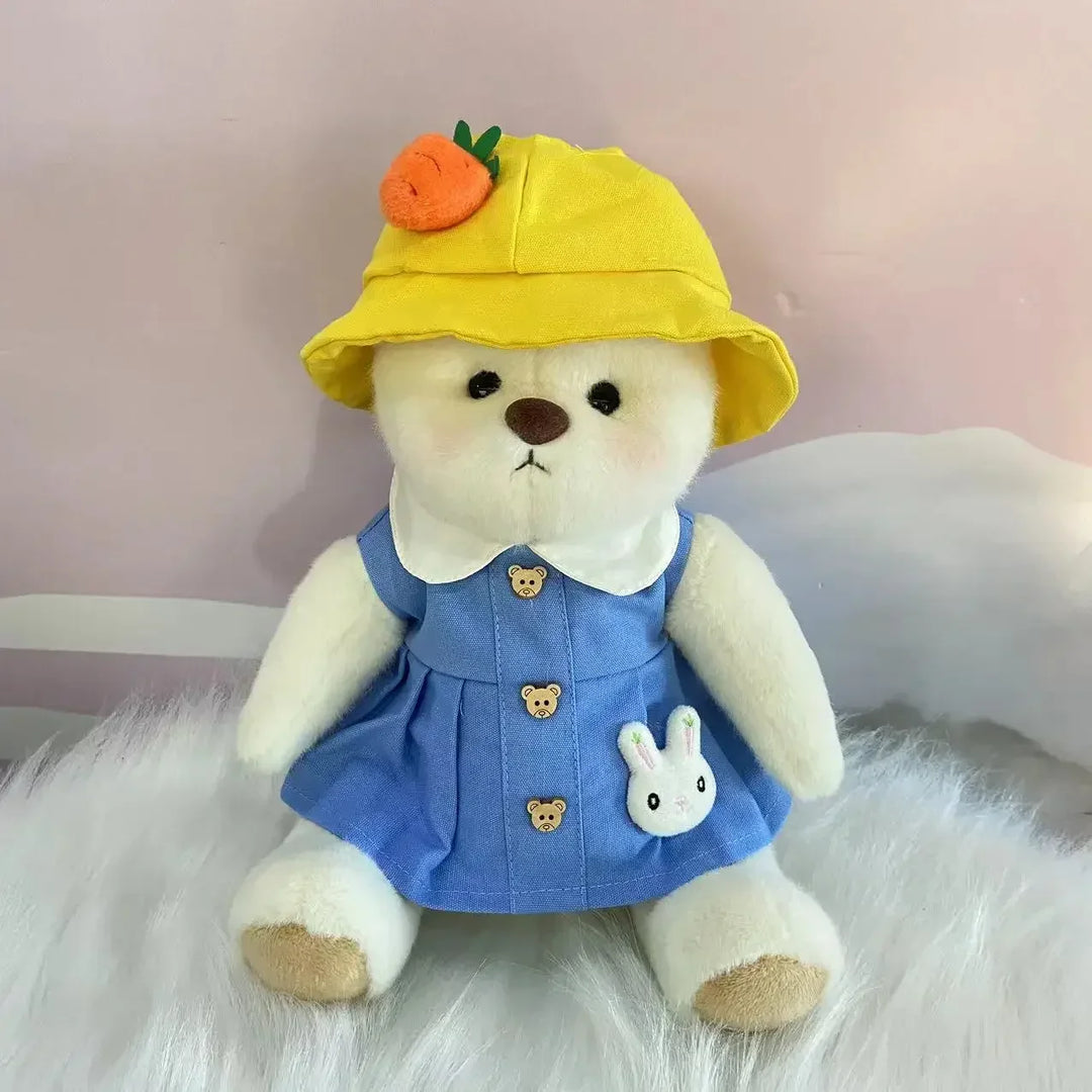 White teddy bear wearing a yellow hat with a carrot, blue dress with bunny design, and white fur background.