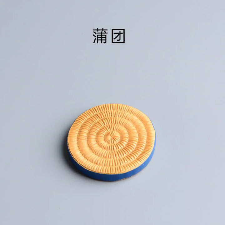 Round woven mat with concentric circles on a gray background.