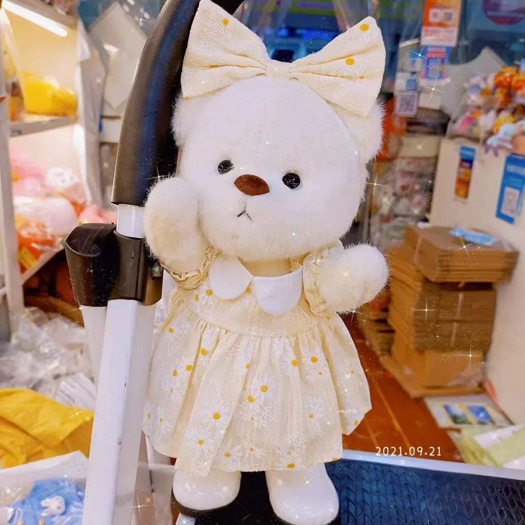 White teddy bear with a yellow bow and dress in a store setting.