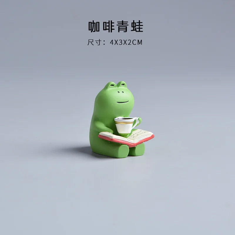 Green frog figurine holding a cup and book on a gray background.