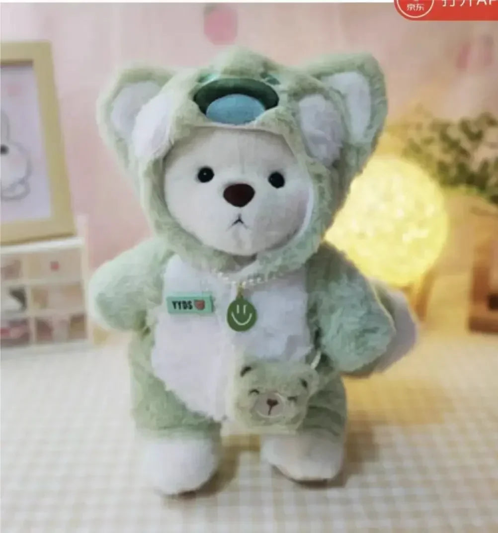 Plush toy bear in a green outfit with a small bear attached, on a soft surface.