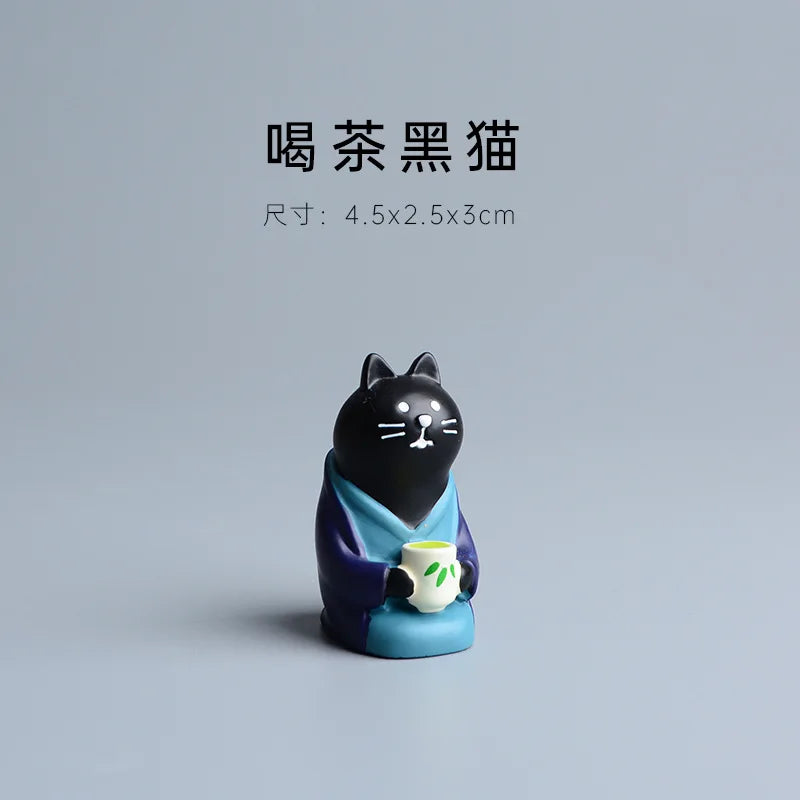 Black cat figurine holding a teacup on a gray background.