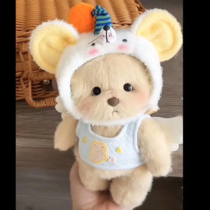 Teddy bear wearing a costume with a small bear on its head, held in a hand against a wooden background.