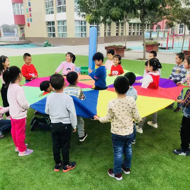 Children playing with a colorful parachute on a playground.