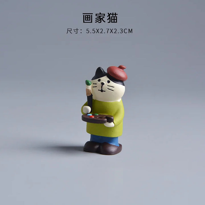 Cat figurine holding a paintbrush and palette on a gray background.