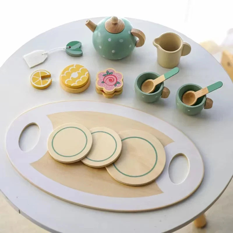 Children's wooden tea set with teapot, cups, and cookies on a white surface.