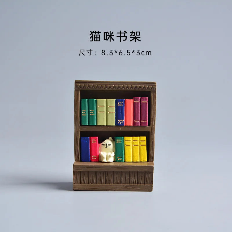 Small wooden bookshelf with colorful books and a cat figurine on a light gray background.
