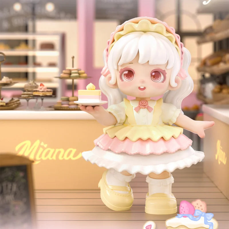 Toy figure of a girl in a yellow dress holding a cake in a bakery setting.