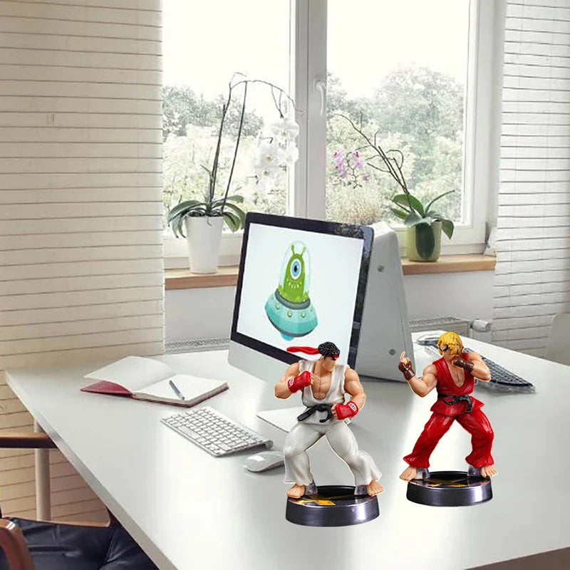 Two action figure statues on a desk with a computer monitor displaying a cartoon character.