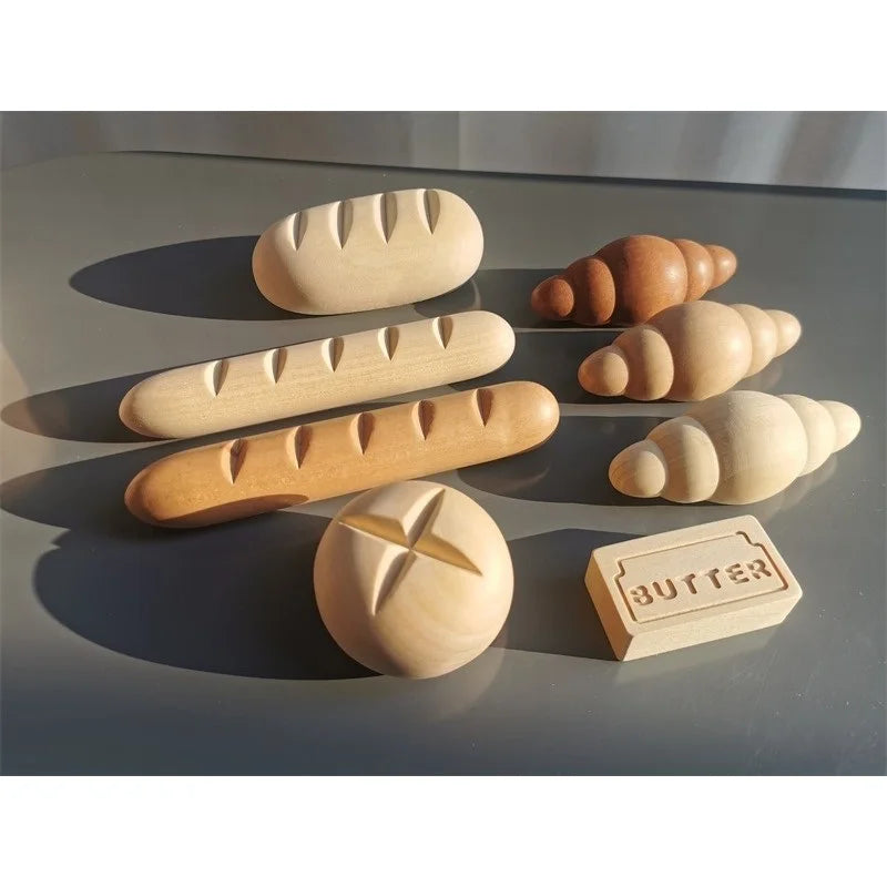 Wooden models of bread and a block labeled butter on a reflective surface.