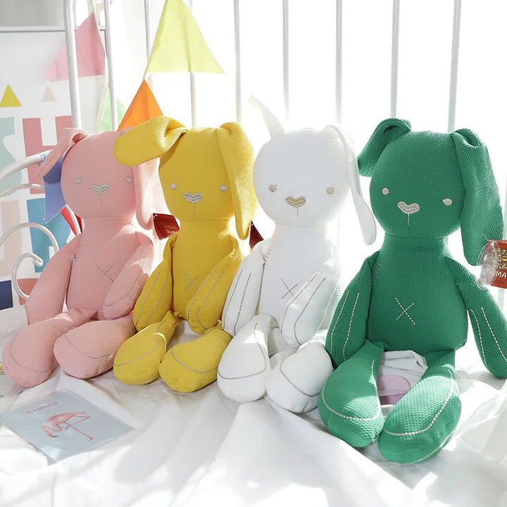 Four colorful plush toys on a white surface with a colorful background.