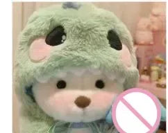 Plush toy with a green hood and pink circle with a red cross over it.