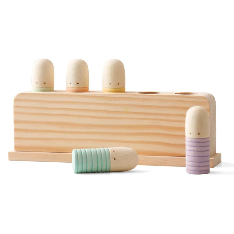 Wooden toy with three cylindrical wooden figures and a rectangular base on a white background.