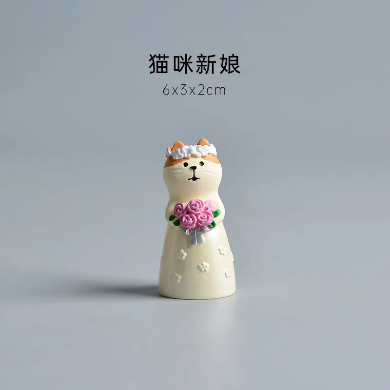 Small decorative figurine of a cat in a wedding dress with flowers on a gray background.