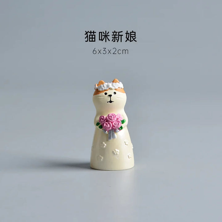 Small decorative figurine of a cat in a wedding dress with flowers on a gray background.