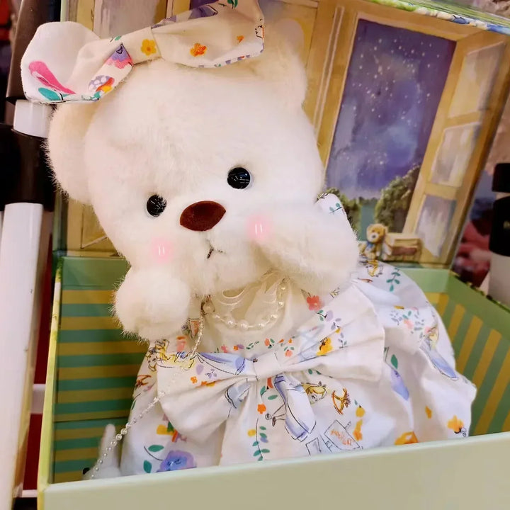 White teddy bear with a floral dress sitting on a colorful surface.