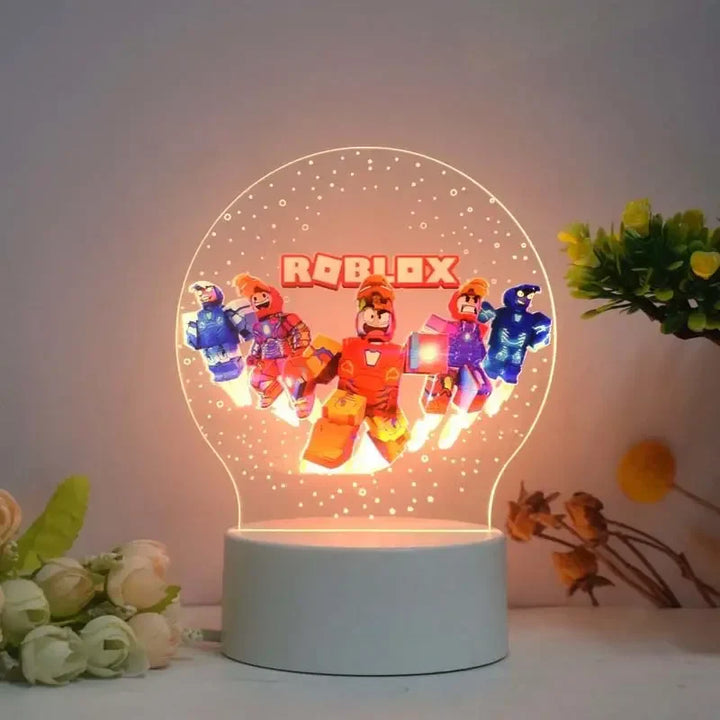 Roblox-themed night light with characters on a white base, surrounded by flowers and plants.