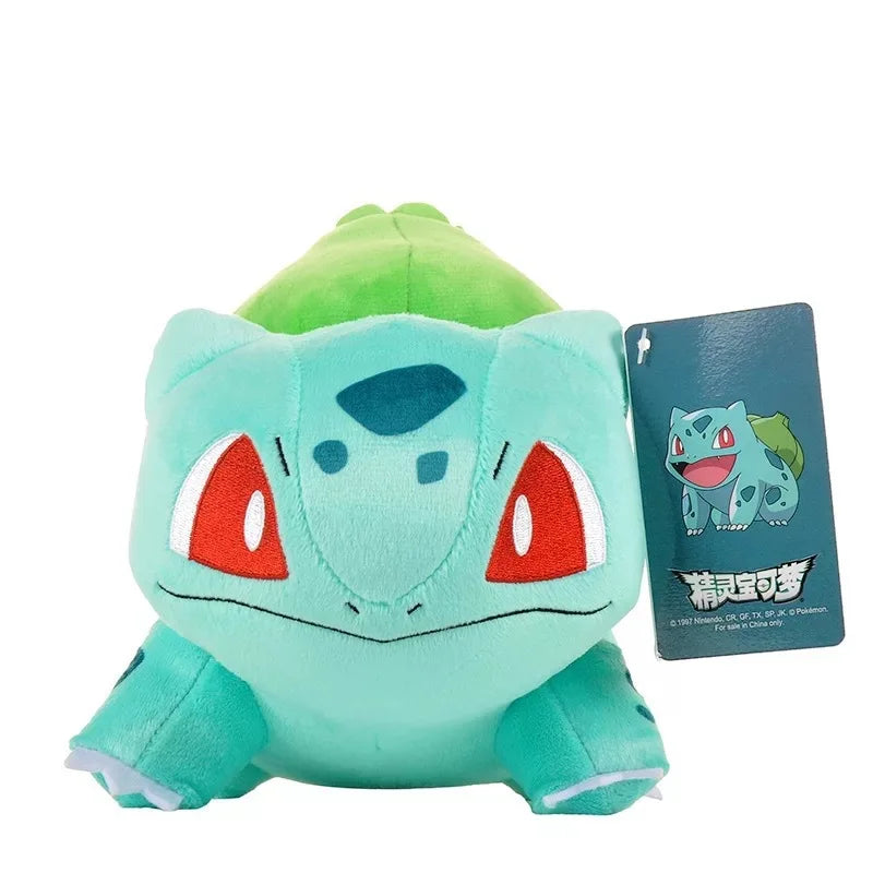 Plush toy of a green creature with red eyes and a tag on a white background.