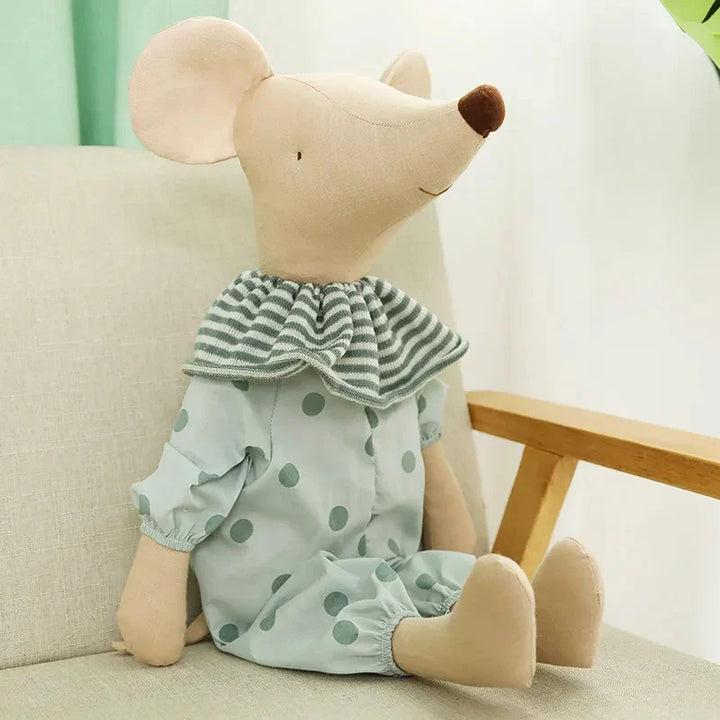 Stuffed toy mouse wearing a green polka dot outfit sitting on a couch.
