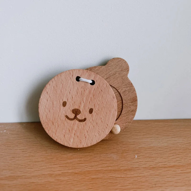Wooden bear-shaped object with a face on a wooden surface.