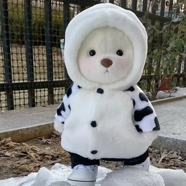Stuffed animal in a white and black outfit standing on snow.