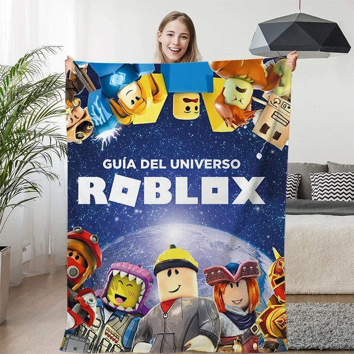 Person holding a Roblox-themed blanket with characters and text in a living room.