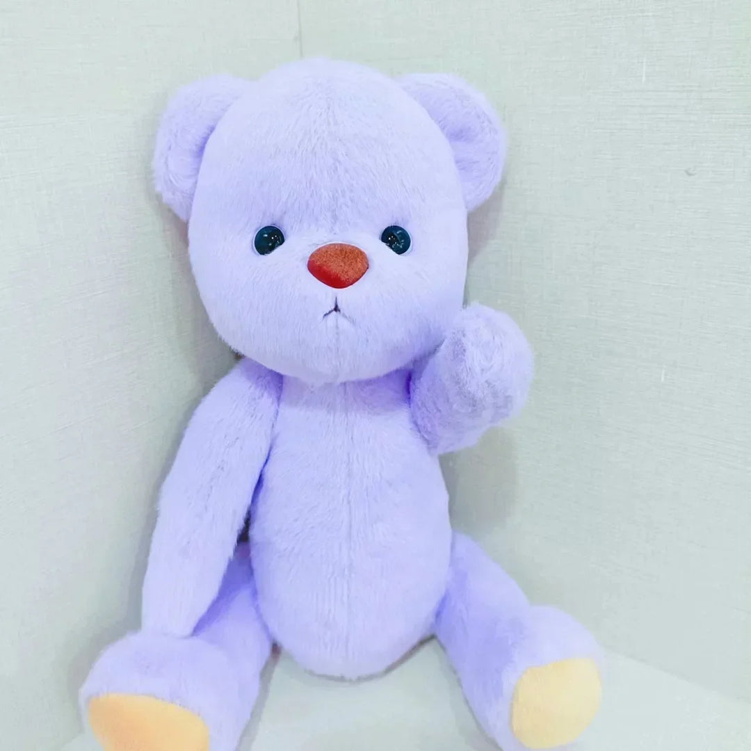 Purple teddy bear with a red nose on a light gray background.
