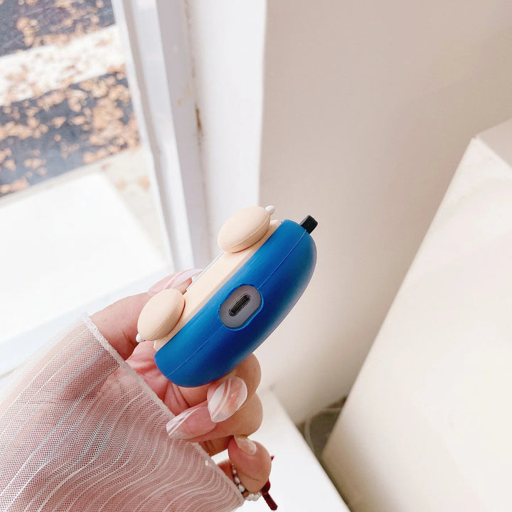 Hand holding a blue and beige electronic device with a blurred indoor background.