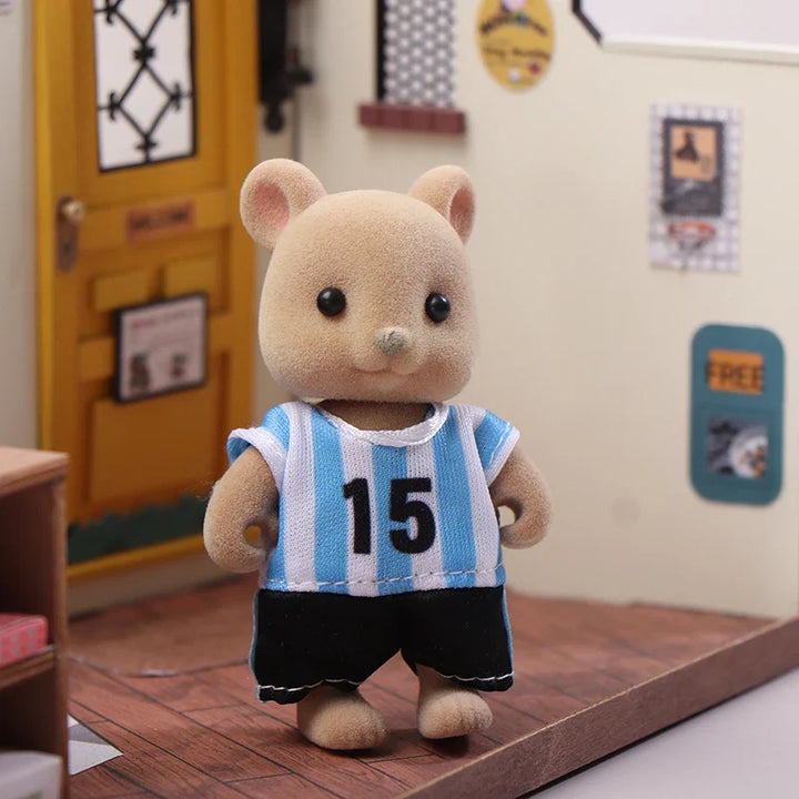 Small teddy bear toy wearing a blue and white striped shirt with number 15 in a room setting.