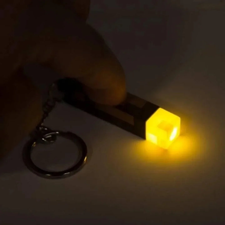 Keychain light emitting a bright yellow glow on a dark background.