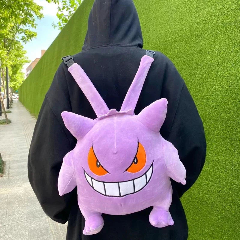 Person wearing a black hoodie with a purple Gengar backpack against a green wall.