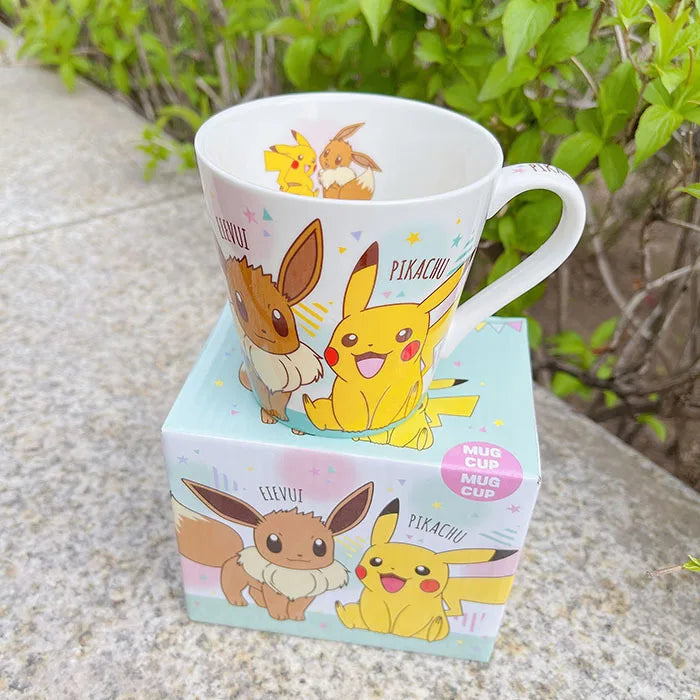 Mug with Pikachu and Eevee designs on a matching box outdoors.