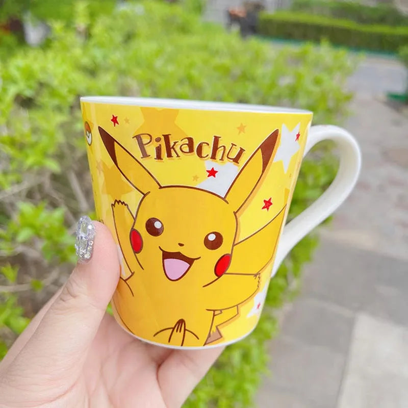 Yellow mug with Pikachu design held by a hand outdoors.
