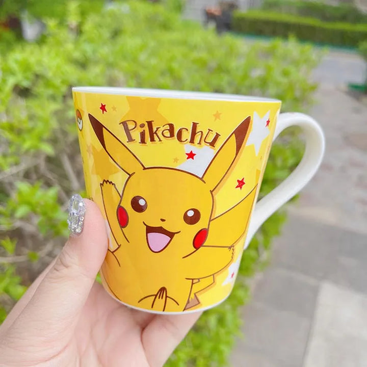 Yellow mug with Pikachu design held by a hand outdoors.