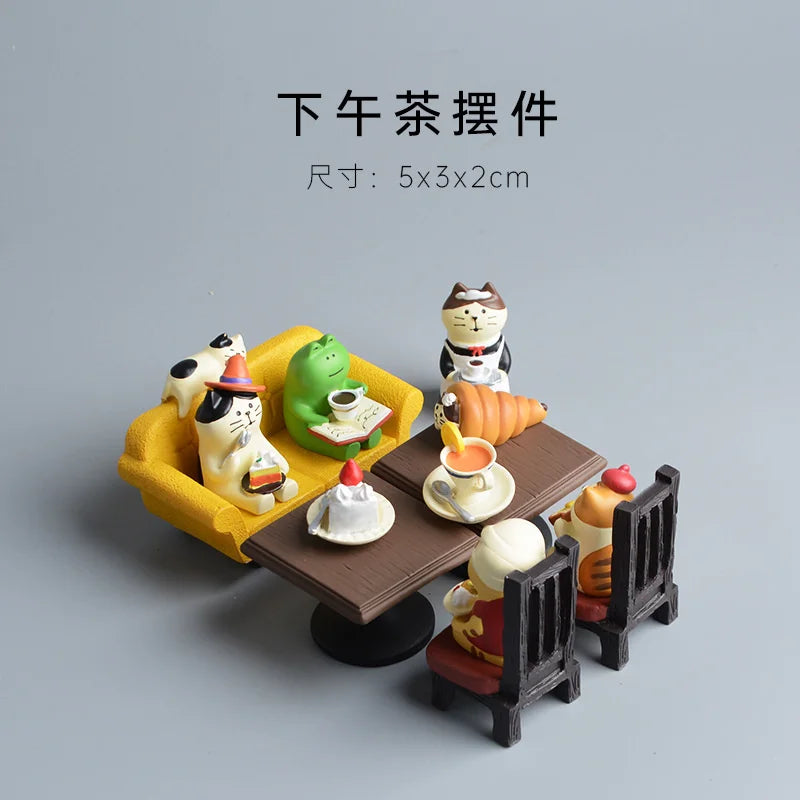 Miniature decorative set with cartoon cat characters around a table on a gray background.