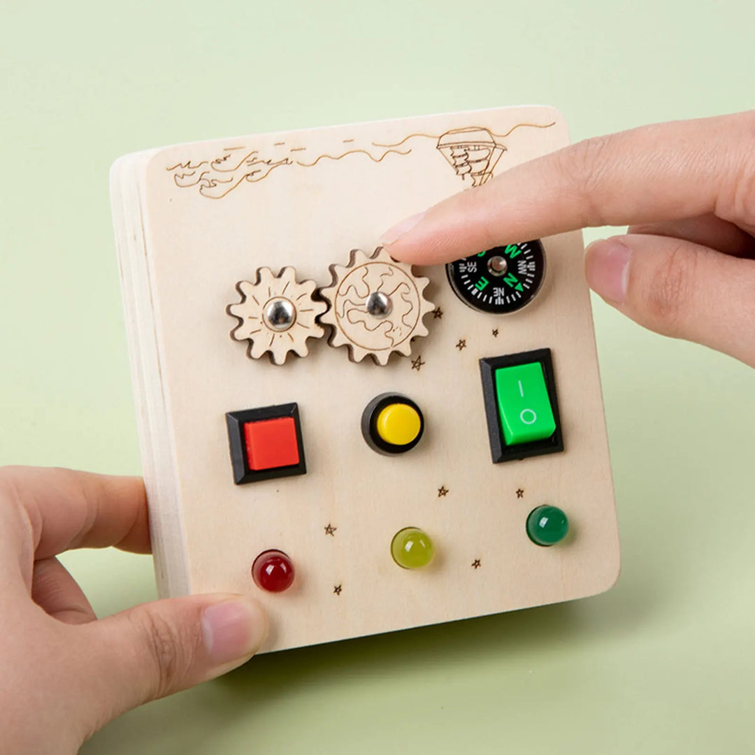 Wooden toy control panel with buttons and a hand interacting with it on a light green background.