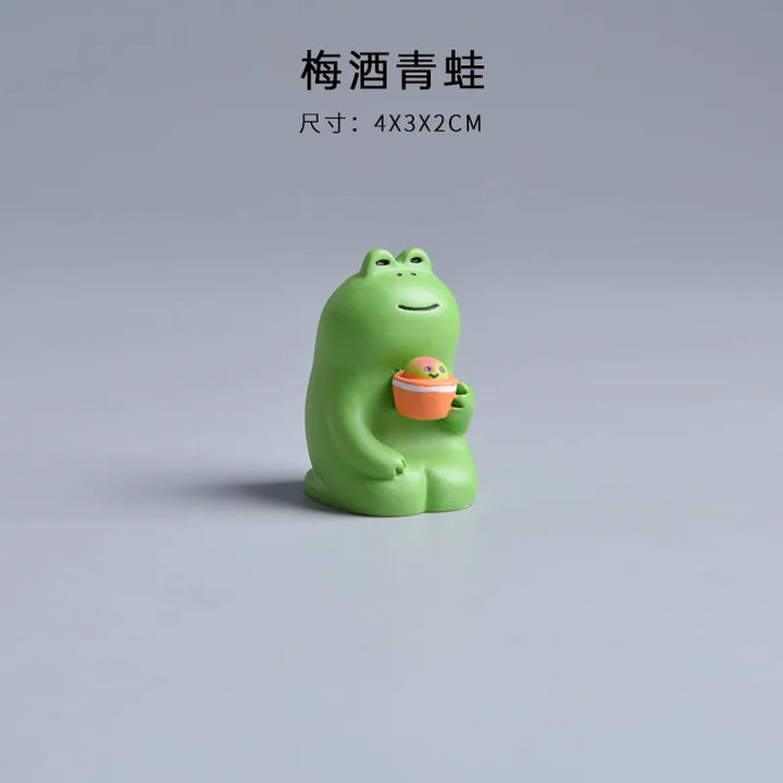 Green frog figurine holding an orange ball on a gray background.