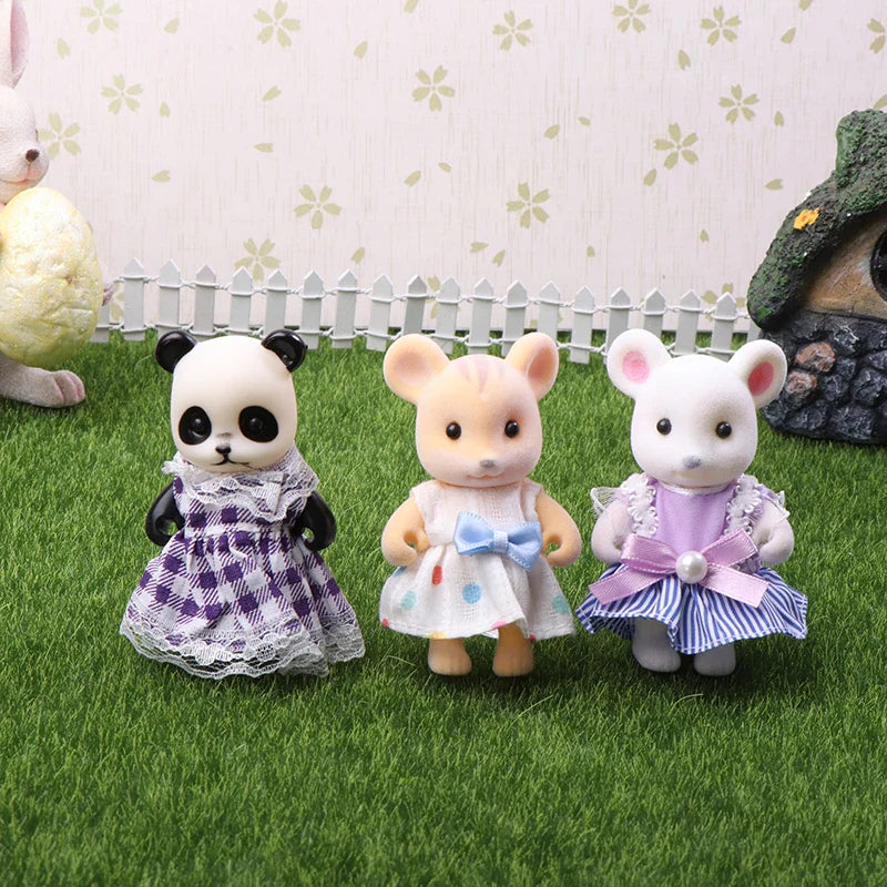 Three toy animals in dresses standing on grass with a decorative background.