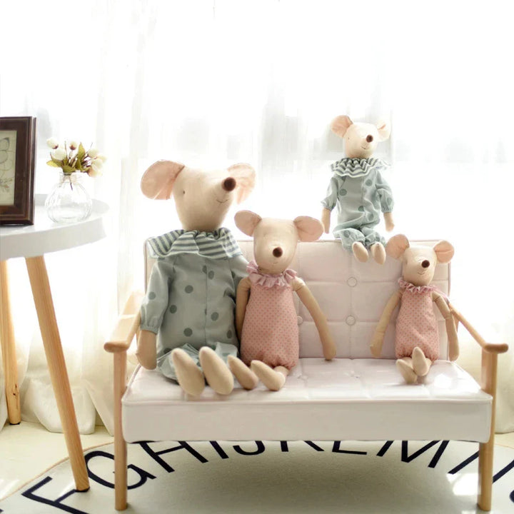 Three plush toy mice sitting on a small white bench in a room with a clock and plant.