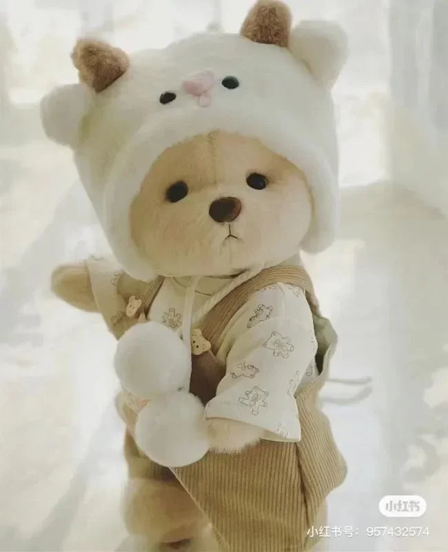 Cute teddy bear plush toy with a white hat and brown outfit on a light background.