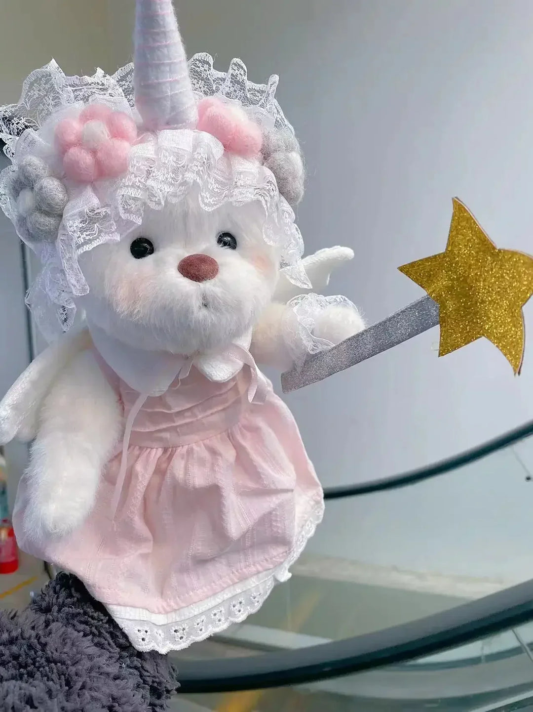 Plush toy with unicorn horn and pink dress on a white background.