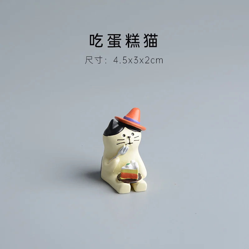 Cat-shaped figurine holding a cake on a gray background.