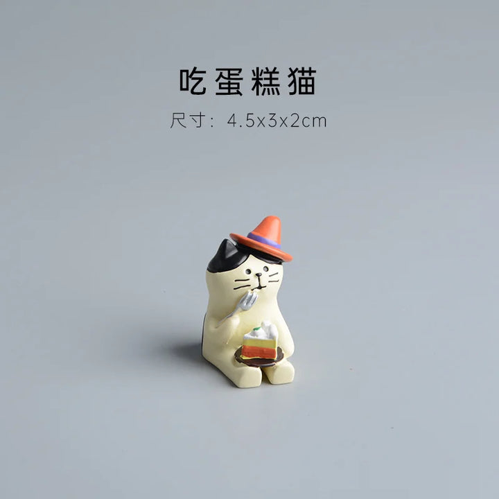 Cat-shaped figurine holding a cake on a gray background.